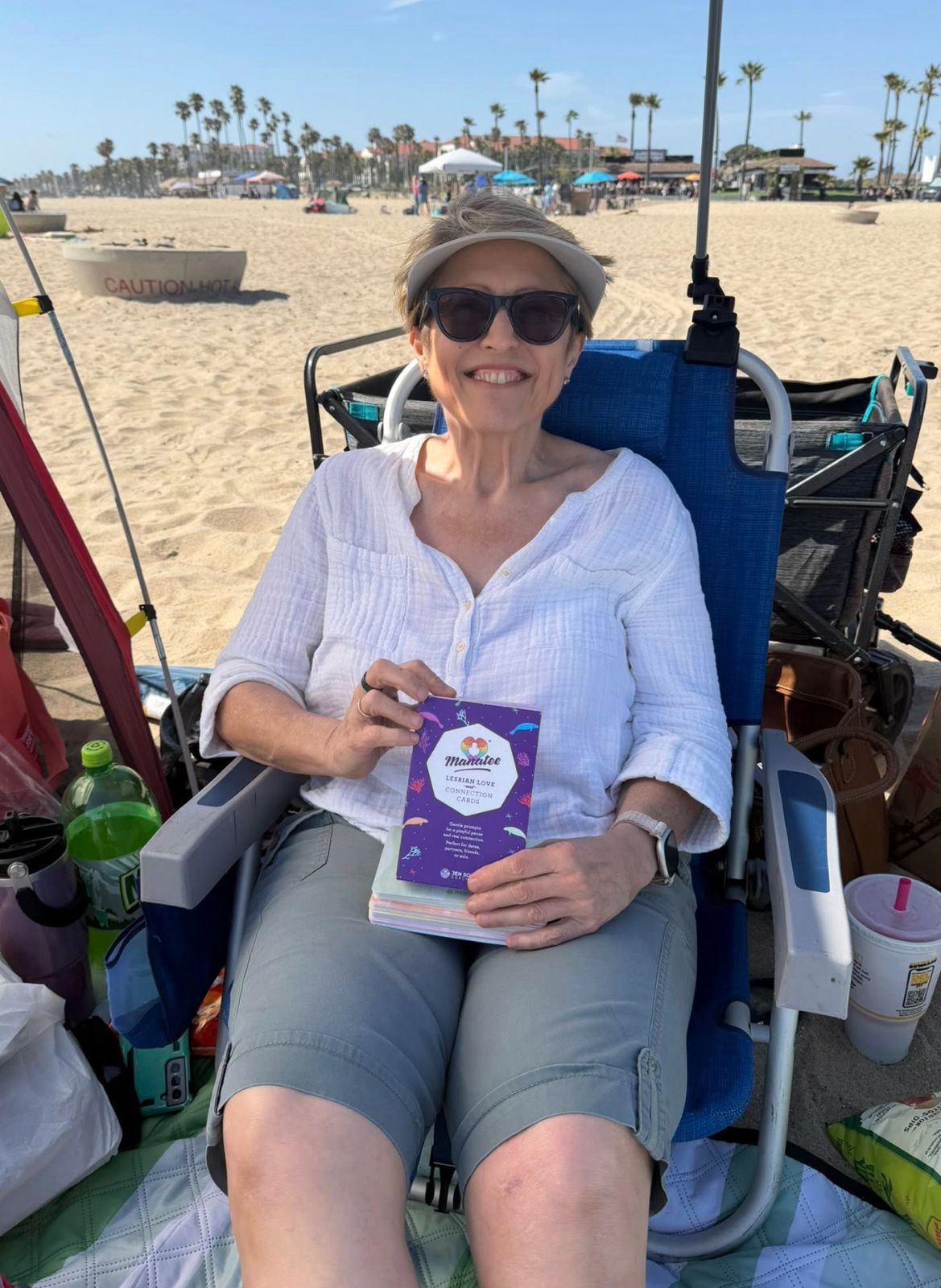 A woman relaxing at the beach with the Manatee deck in hand