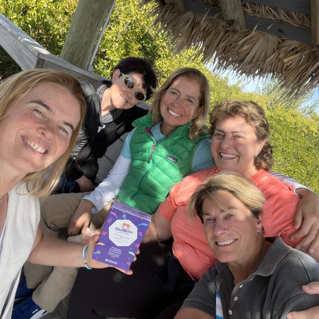 Five friends at a beach hut holding the Manatee deck